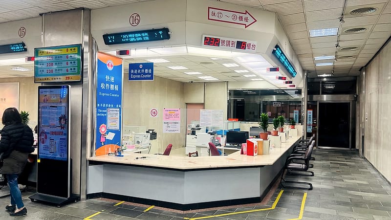 An express service counter in a government office with staff seated behind numbered windows and a queue barrier in front.