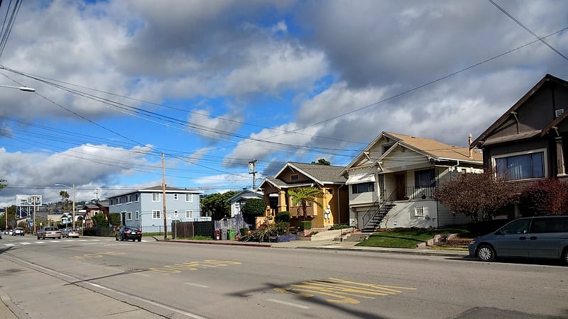 A row of similar suburban houses with uniform roof lines, driveways and front lawns along a residential street.