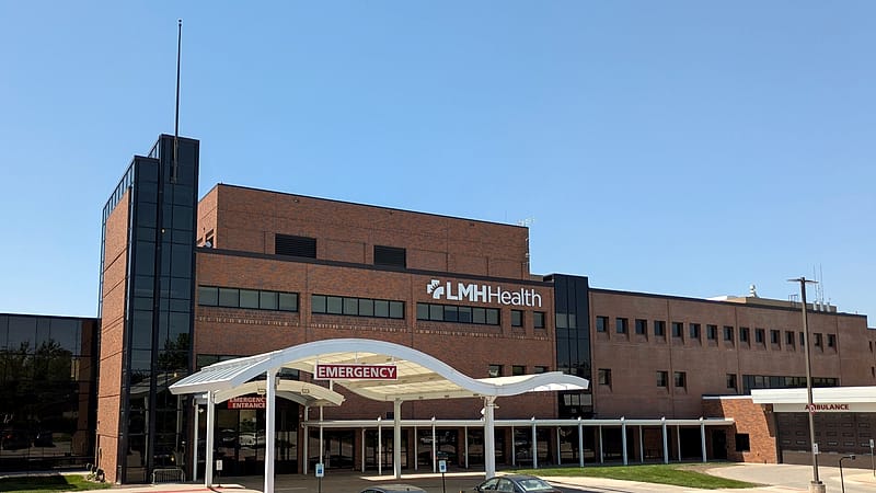 The ambulance entrance of a hospital at dusk, with signage above the covered bay and no vehicles present.