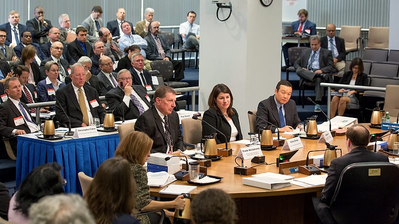 A hearing room with a raised bench, microphones and a table for parties in a state administrative building.