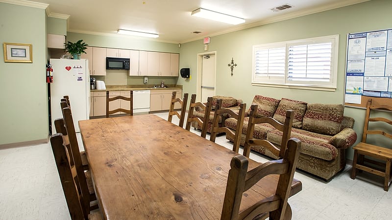 A small rural clinic building with a gravel parking lot and a single ambulance parked outside.