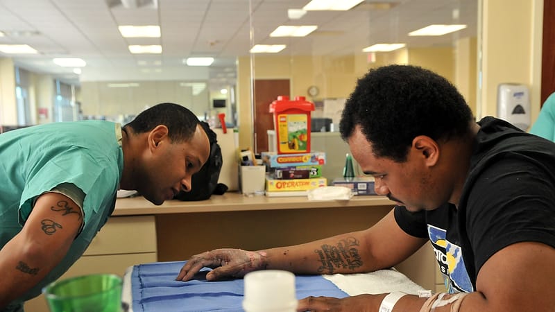 A therapist guides a patient's hand through a range-of-motion exercise in a rehabilitation clinic.