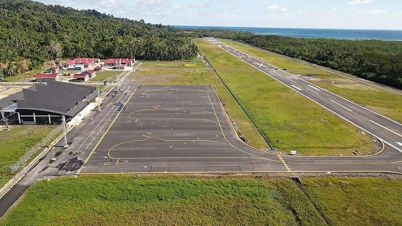 A single-engine light aircraft parked on an airfield apron with its registration mark visible along the rear fuselage.