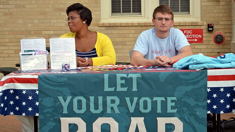 A registration table at a community event with clipboards, forms and a folding chair set out for volunteers.
